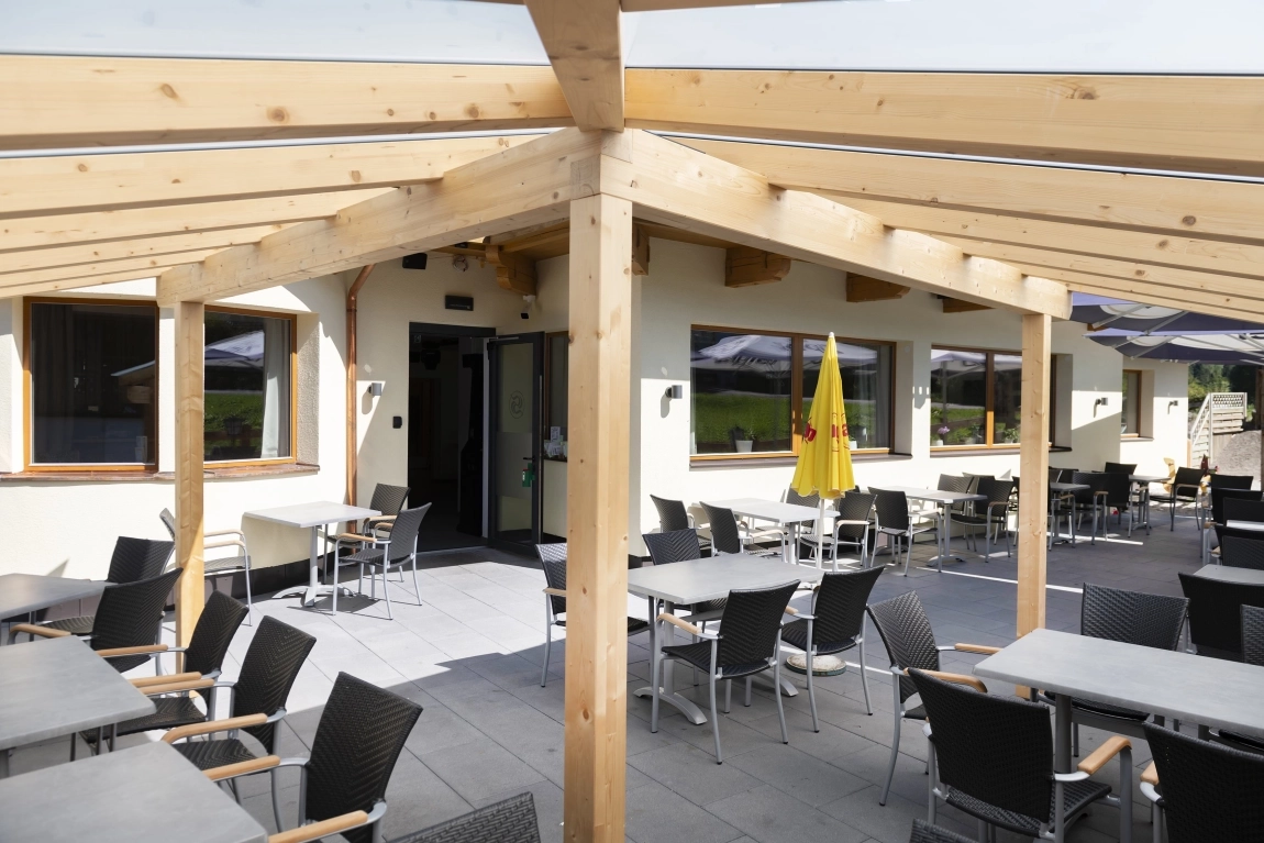 Überdachte Terrasse mit vielen Sitzplätzen, barrierefreiem Zugang und direkter Verbindung zum Gebäude.