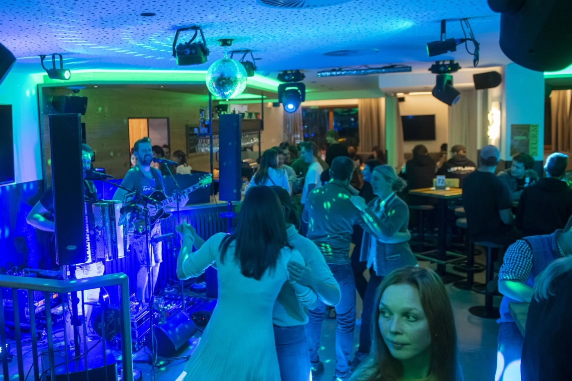 Livemusik und Tanz in der Hotelbar mit grüner Beleuchtung, Gästen auf der Tanzfläche und an Stehtischen.
