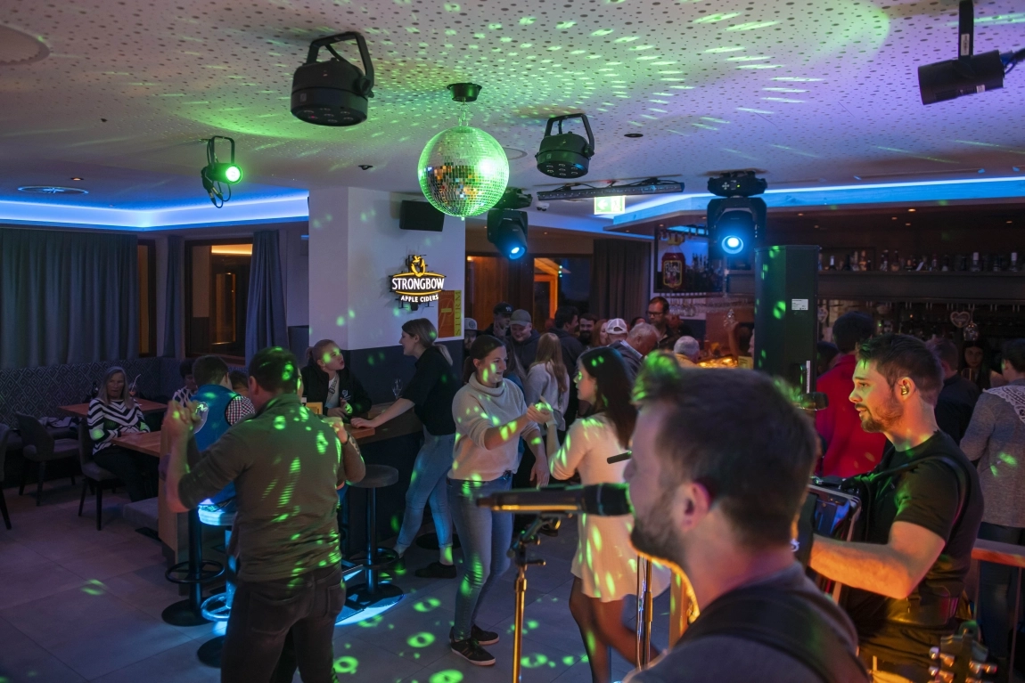 Abendveranstaltung mit Livemusik, Tanzenden, Discokugel und Lichteffekten in der Bar des Hotels.