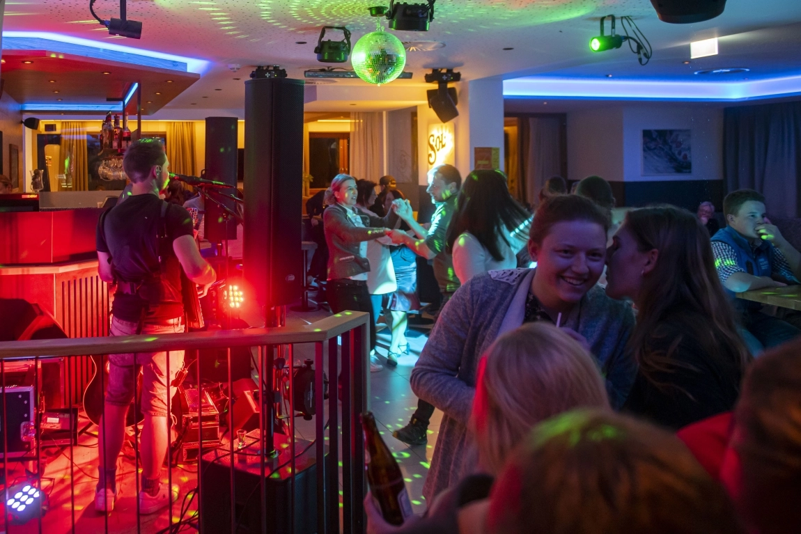 Abendliche Livemusik in der Hotelbar mit Tanz, Gesprächen, Discokugel und bunter Beleuchtung