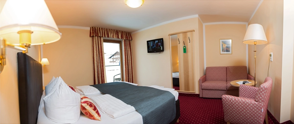 Hotelzimmer mit kontrastreichem rotem Teppich, hellen Wänden, guter Beleuchtung und klar erkennbaren Möbeln.