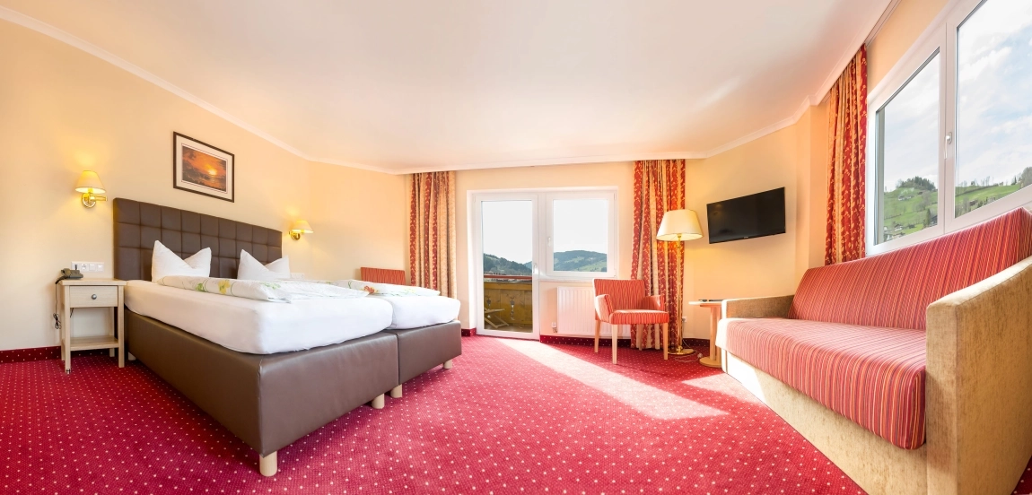 Helles Zimmer mit rotem Teppich, kontrastreichen Möbeln, großem Fenster für Tageslicht und barrierefreier Raumaufteilung.