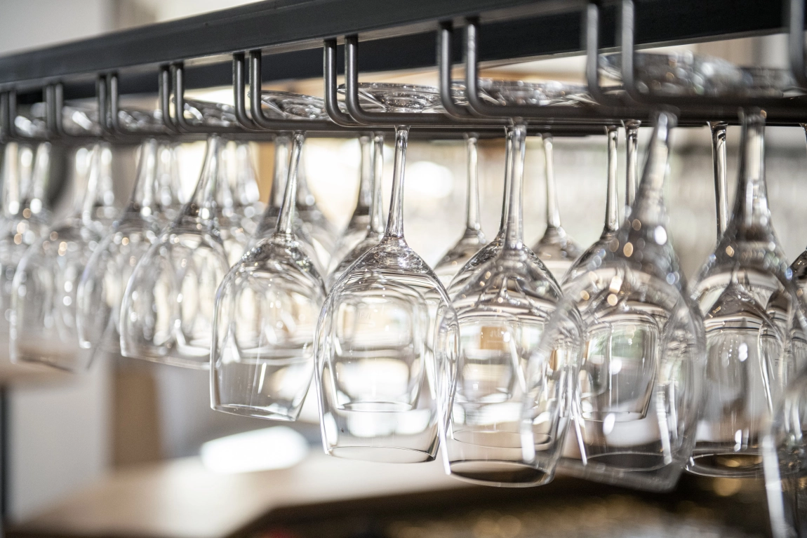 Reihe sauber aufgehängter Weingläser über einer Bar – elegantes Detail aus dem Innenraum der dorfStub’n.