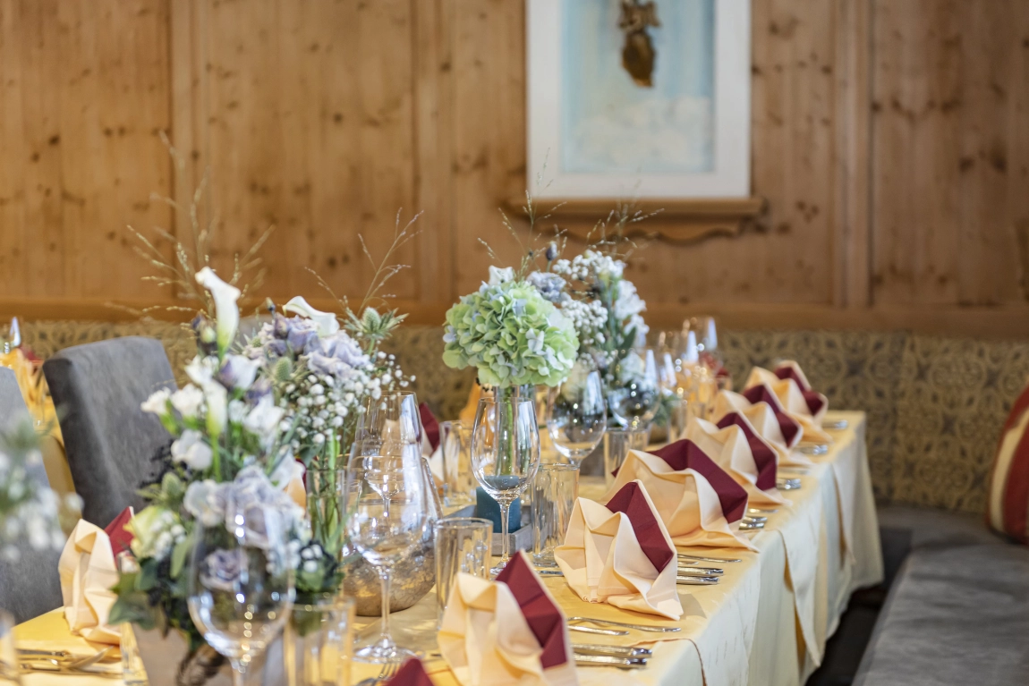 Festlich gedeckter Tisch im Hotelrestaurant mit Blumen, Gläsern, Besteck und kunstvoll gefalteten Servietten.